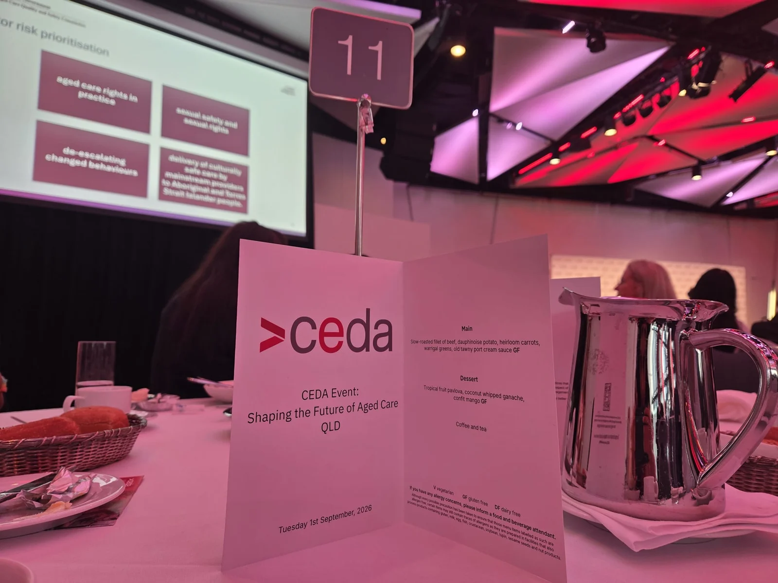 CEDA Shaping the Future of Aged Care QLD programme on a conference table, with the presentation screen in the background